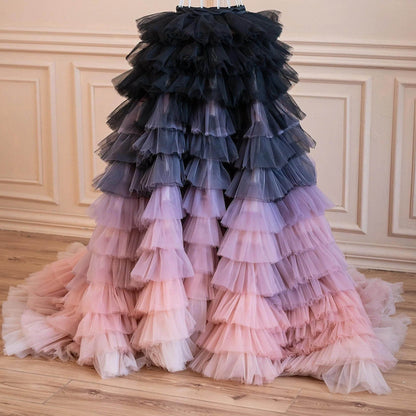 A long, voluminous, ruffled dress with a gradient of colors, transitioning from black to pink and purple.