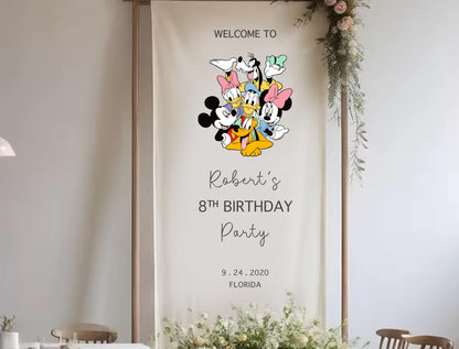 The image is a banner for a birthday party featuring a group of Disney characters, including Mickey Mouse, Minnie Mouse, Donald Duck, and Goofy. The banner is set against a white background and has text welcoming guests to the party.