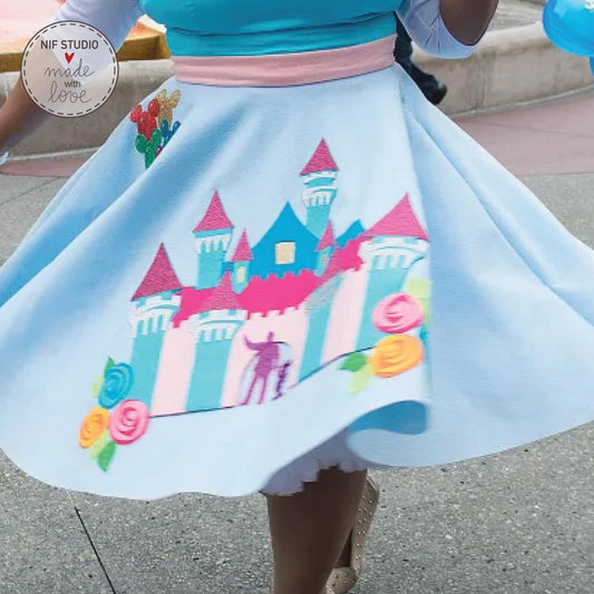A woman wearing a blue dress with a castle design on it, walking on a sidewalk.