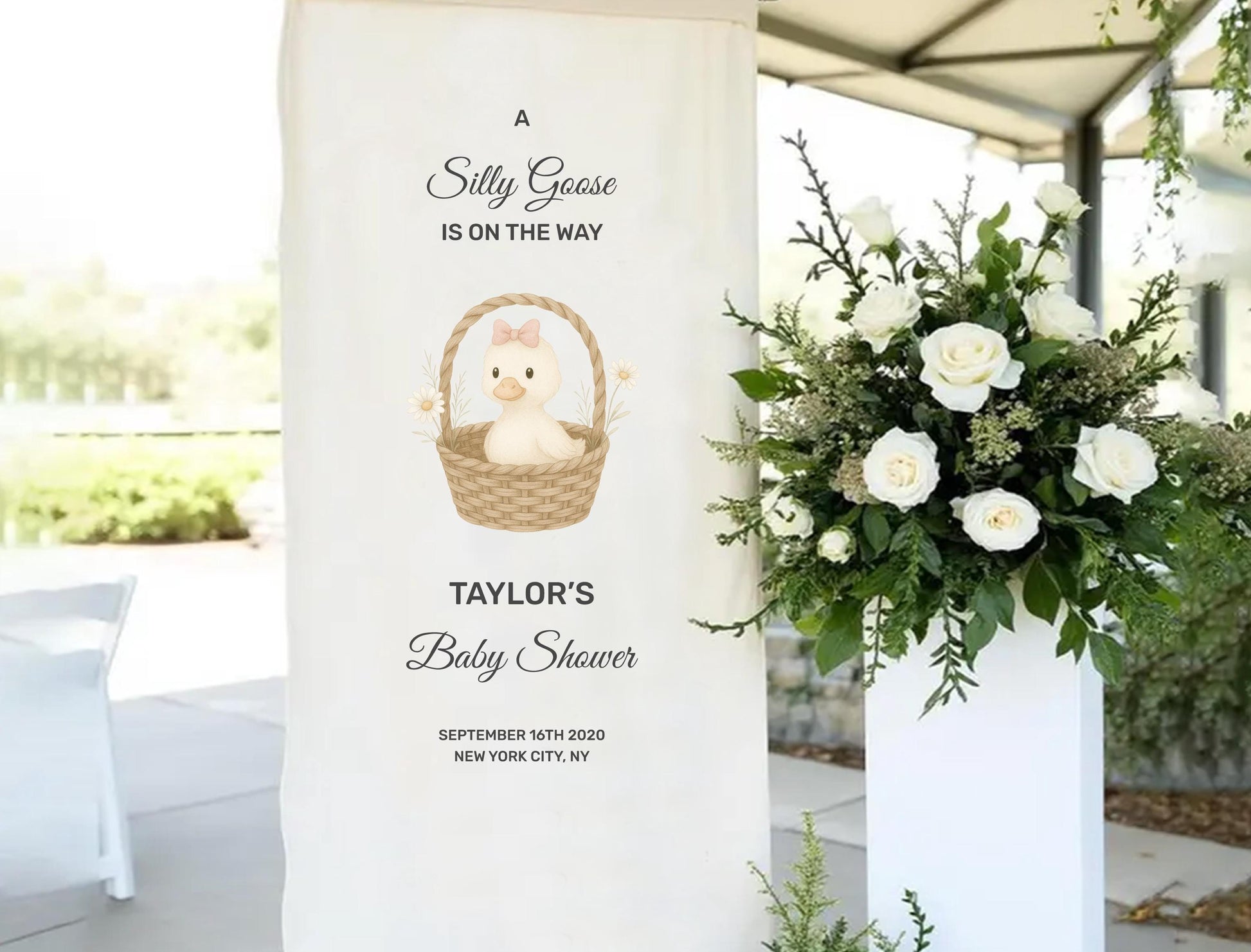 A banner for a baby shower, featuring a cartoon image of a baby in a basket and text announcing the event.