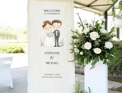 a wedding invitation sign with a bride and groom illustration, placed next to a floral arrangement.