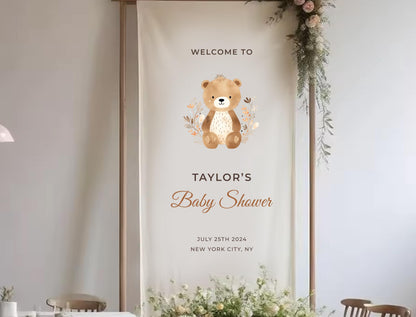 The image is a banner for a baby shower, featuring a teddy bear and floral decorations.