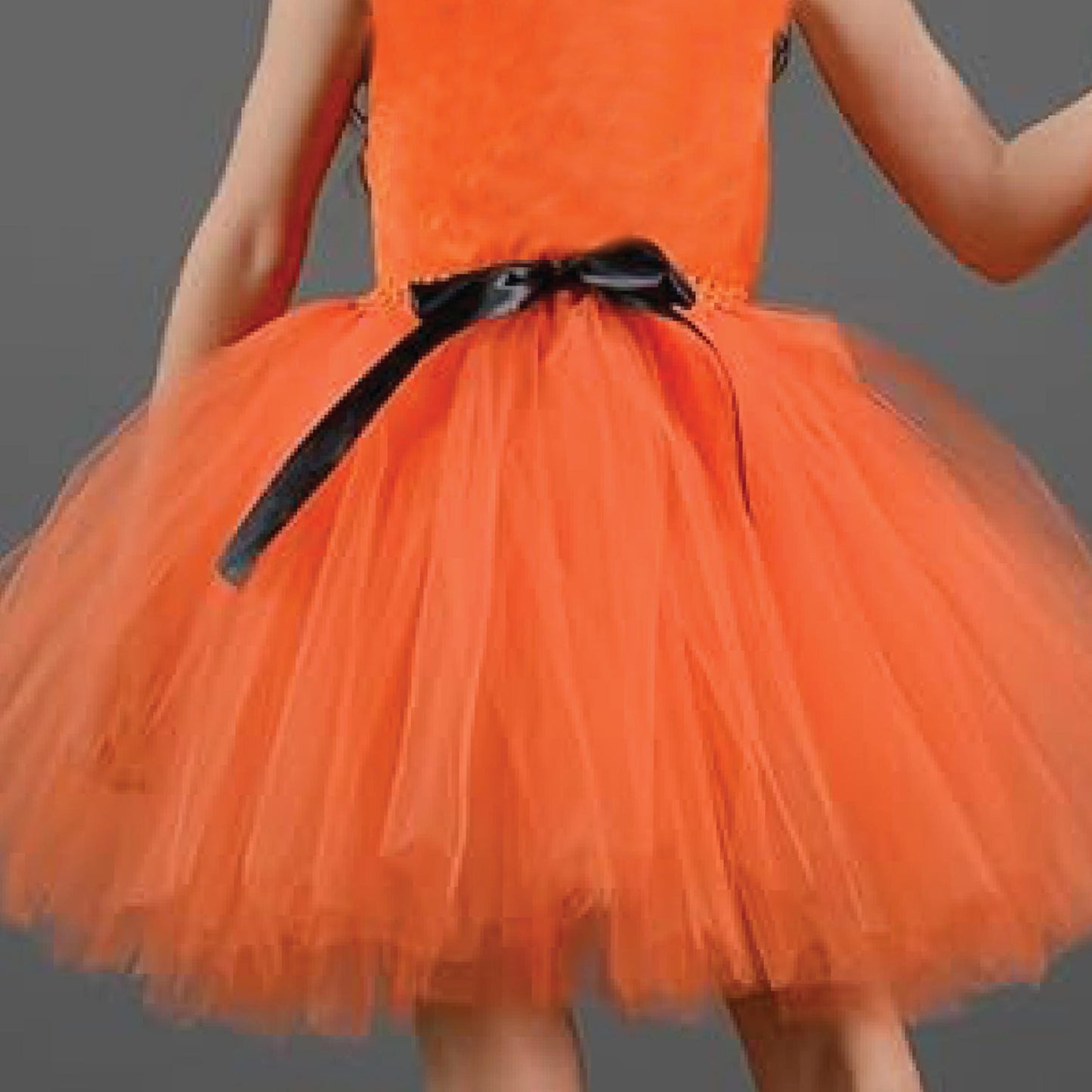 A close-up of a young girl wearing an orange tutu dress with a black bow.